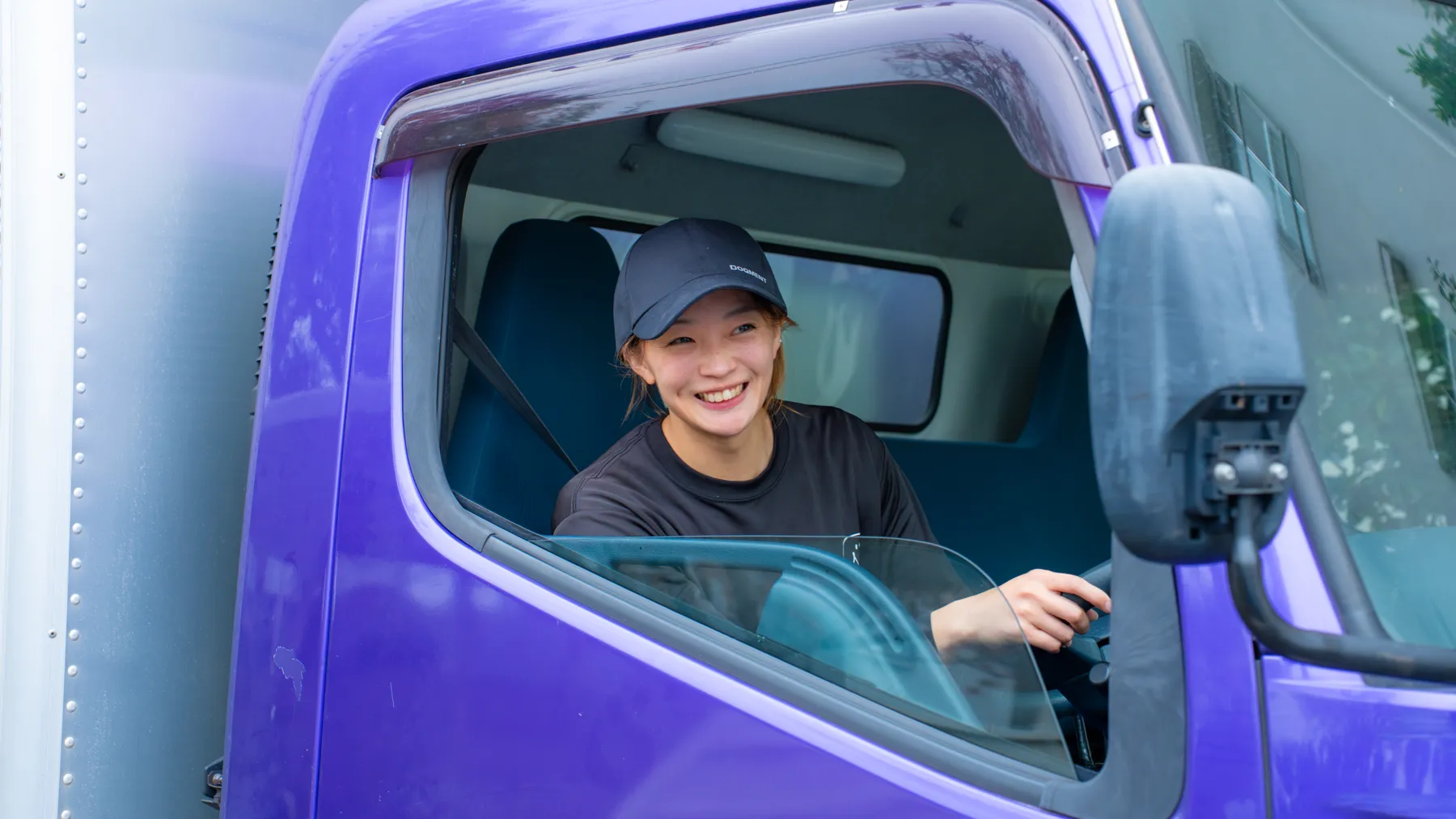 トラックの運転席から笑顔で顔を出す代表 柳澤 夏希